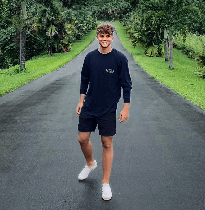 Biaheza standing on a dark asphalt road against a stunning green backdrop of tropical trees and bright green grass