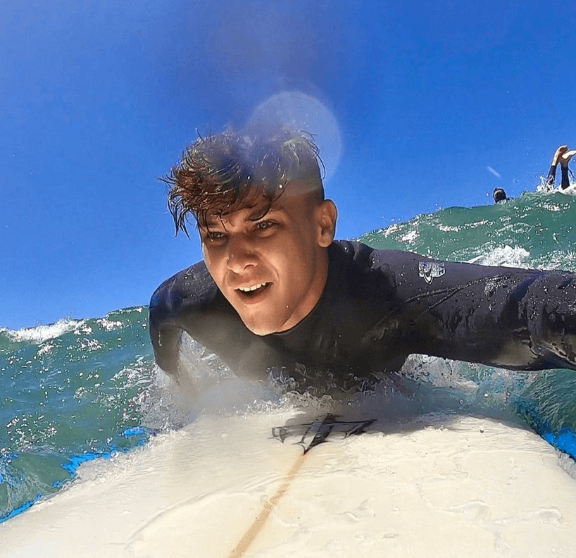 Biaheza laying down on a white surf board in the ocean paddling getting ready to catch a wave